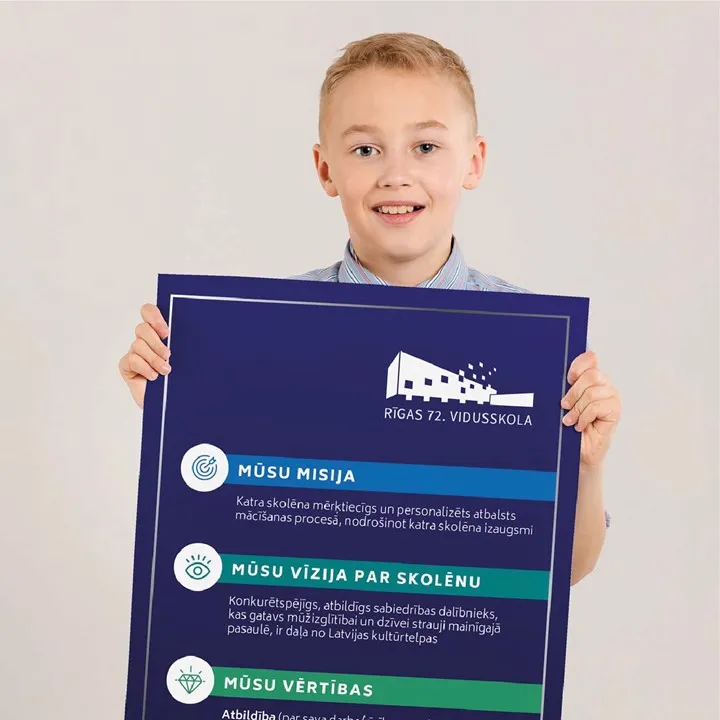 A boy holding large poster with key values of Rigas 72. vidusskola